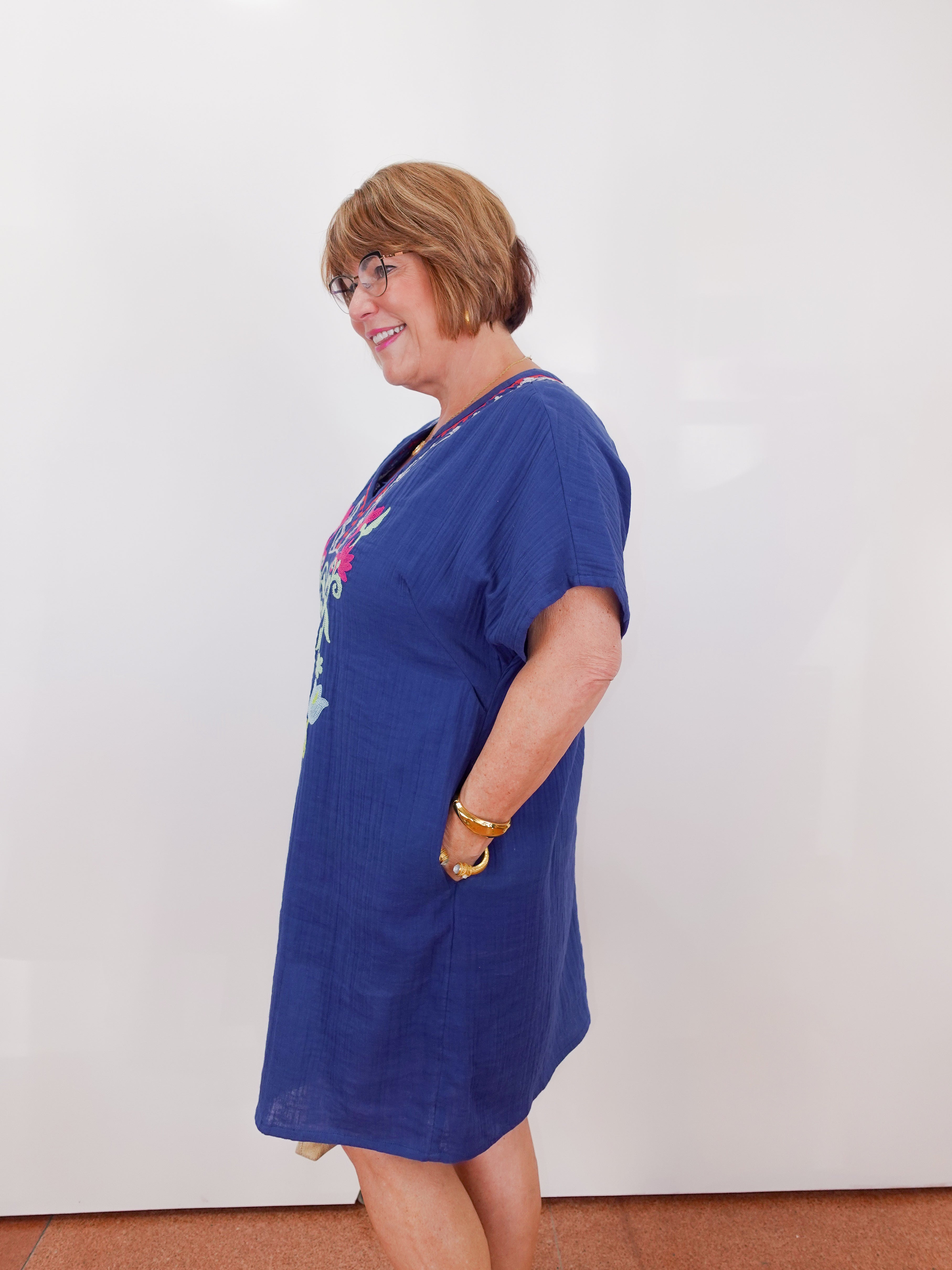 Woman wearing a blue dress with a colorful graphic on a plain background