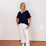 Person wearing a navy top and white pants against a plain background