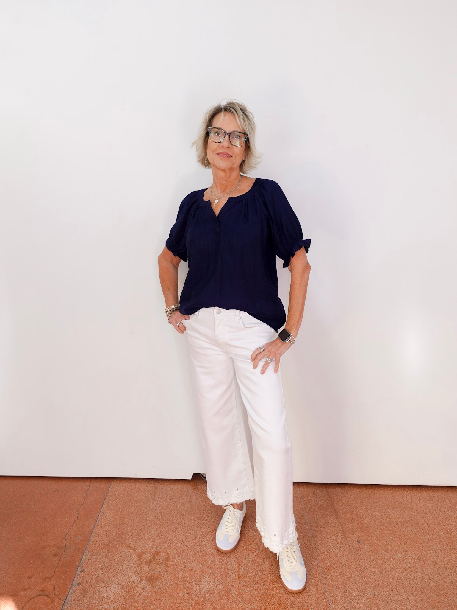 Person wearing a navy top and white pants against a plain background