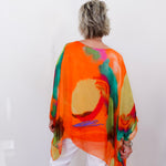 Person wearing a colorful, abstract-patterned orange garment against a white background
