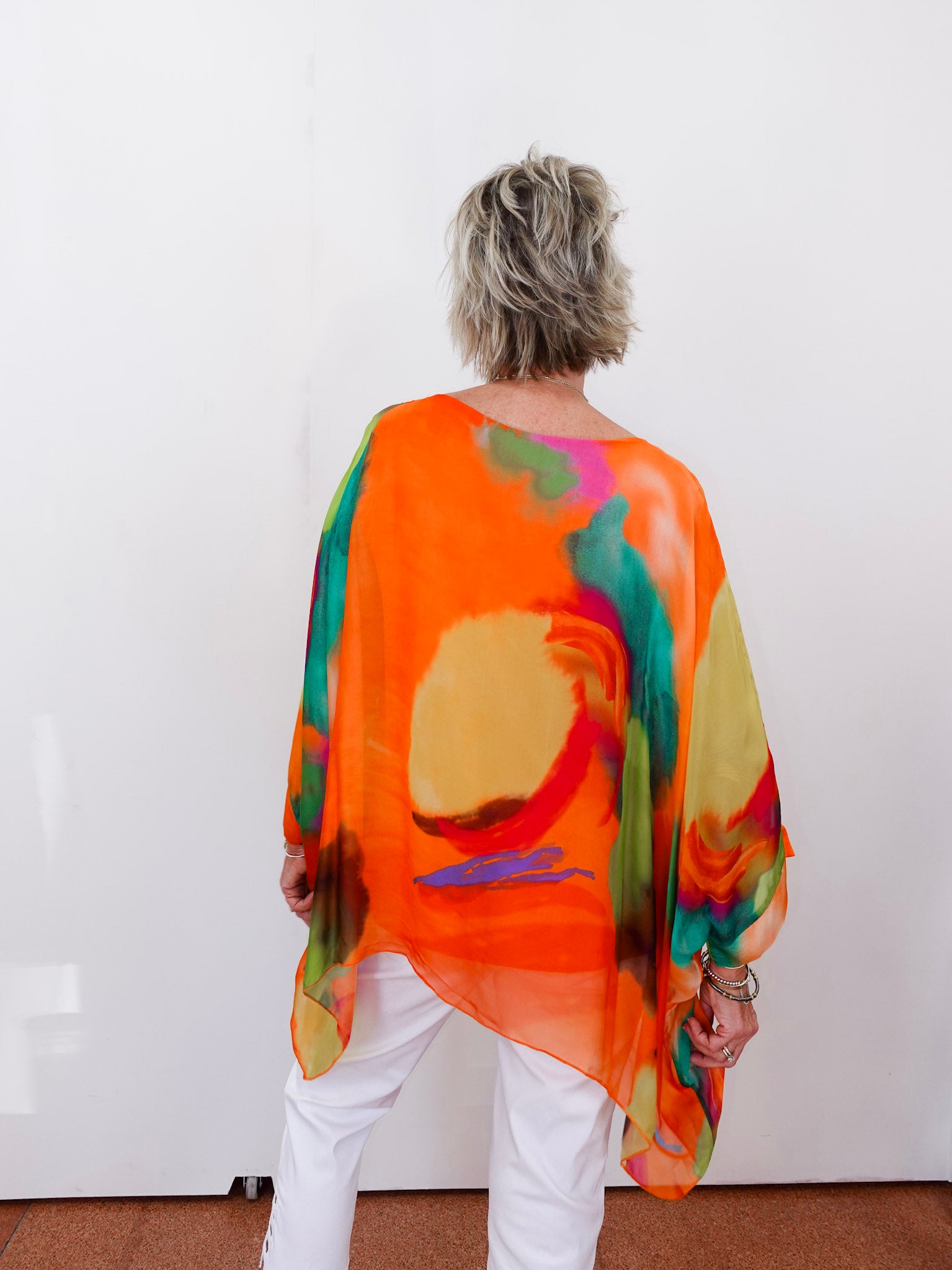 Person wearing a colorful, abstract-patterned orange garment against a white background