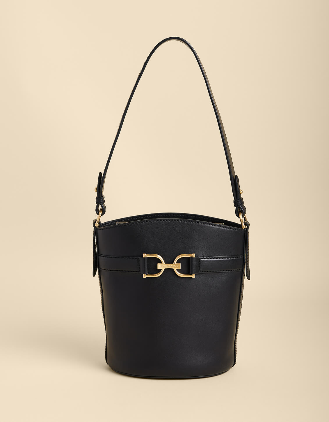 Black handbag with gold hardware on a beige background