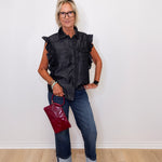 Woman wearing a black sleeveless shirt, blue jeans, and holding a red handbag against a white background