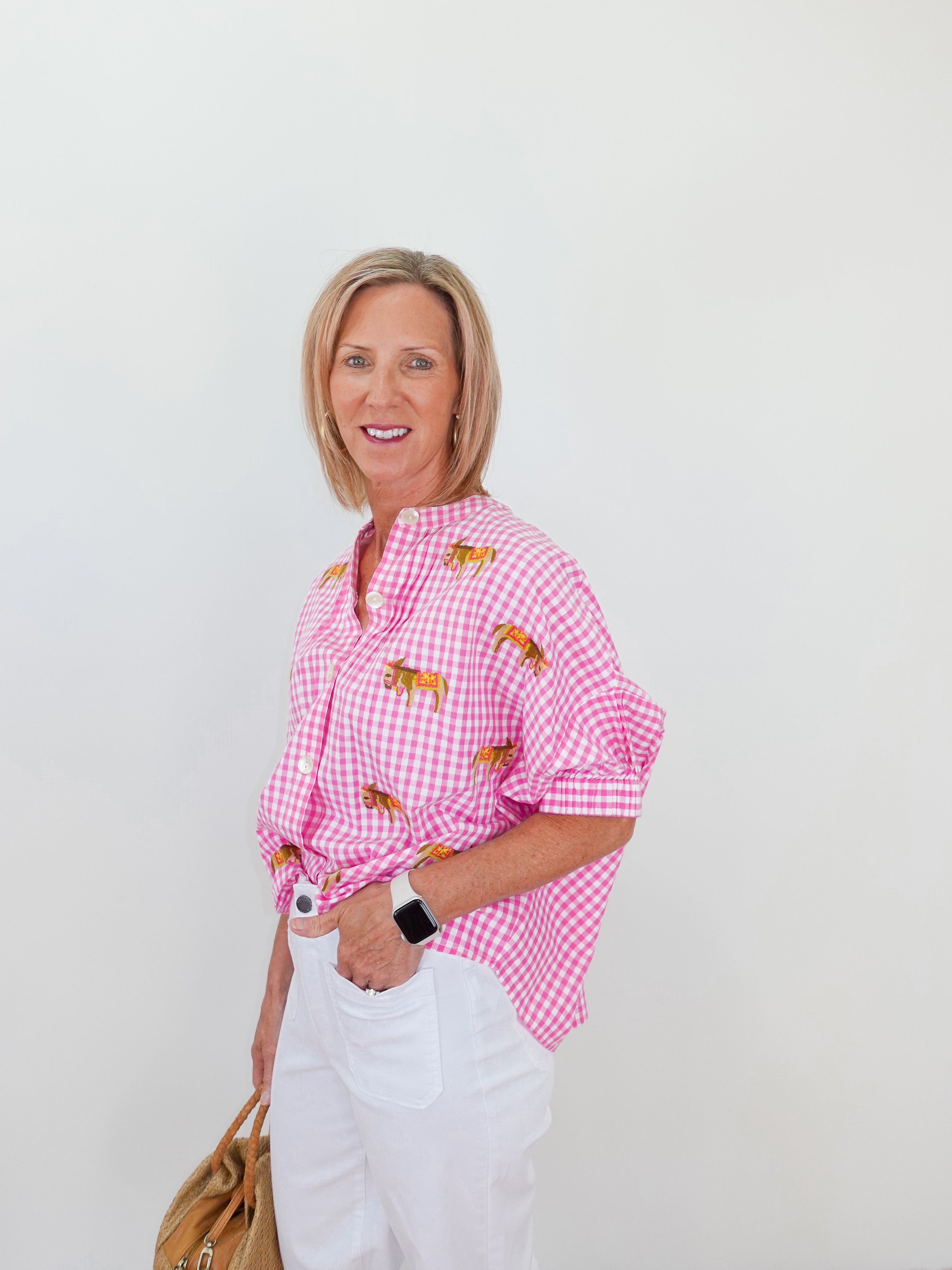 Woman wearing a pink checkered shirt with embroidered details on a white background