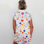 Person wearing a colorful floral patterned outfit on a plain background