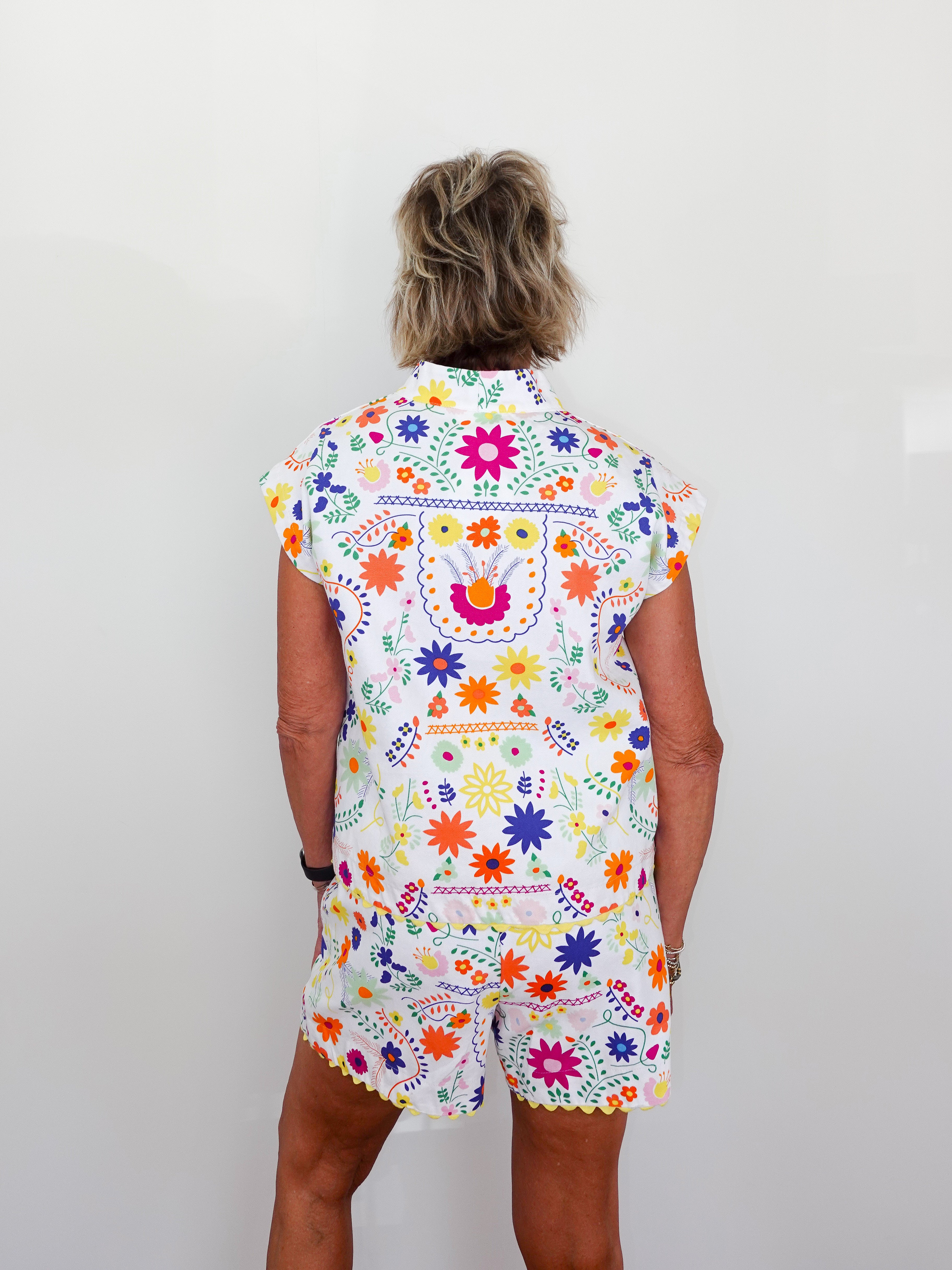 Person wearing a colorful floral patterned outfit on a plain background