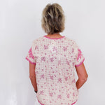 Woman wearing a white blouse with pink floral patterns on a white background