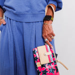 Person wearing a blue outfit holding a colorful star-patterned clutch bag.
