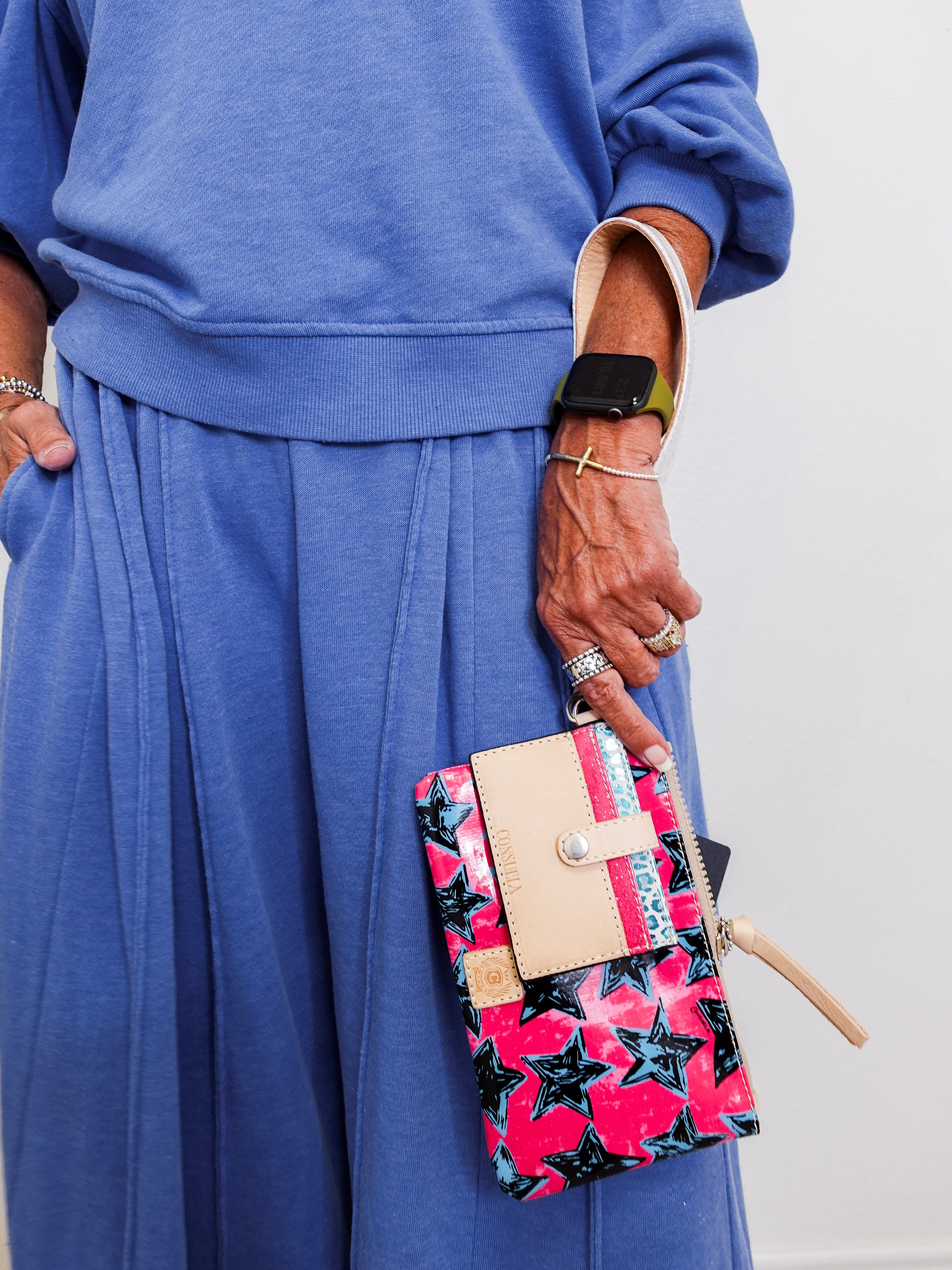 Person wearing a blue outfit holding a colorful star-patterned clutch bag.