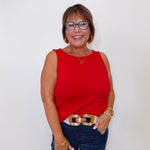 Woman wearing a red sleeveless top and blue jeans against a white background