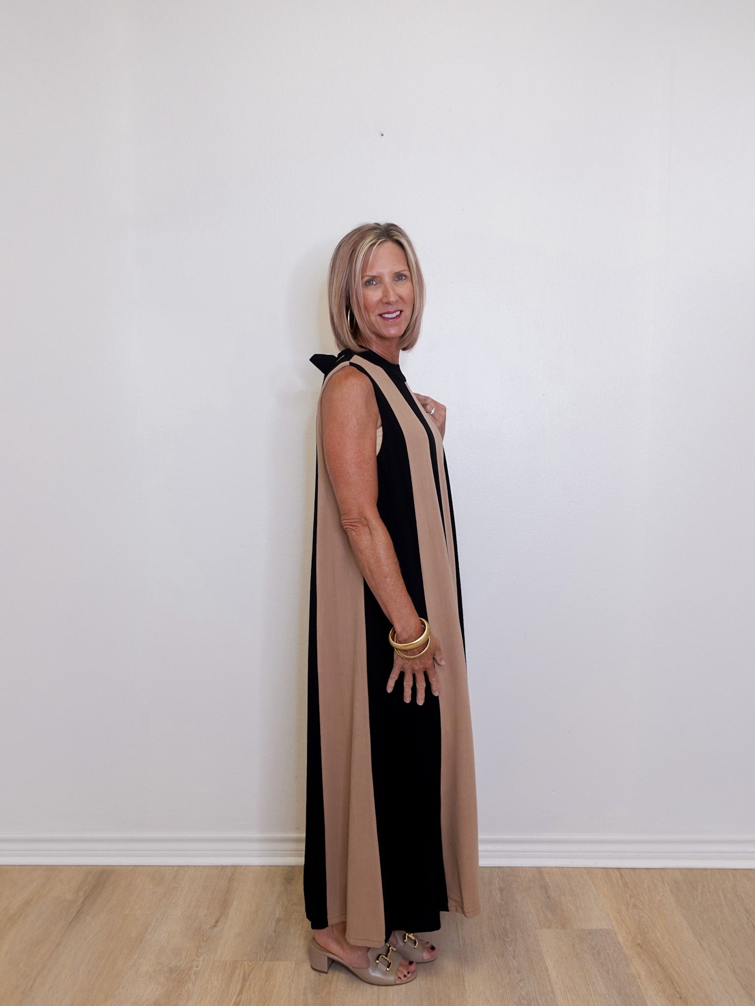 Women's sleeveless maxi dress with black and taupe colorblock design against a white background. 