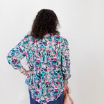 Person wearing a colorful floral blouse against a white background