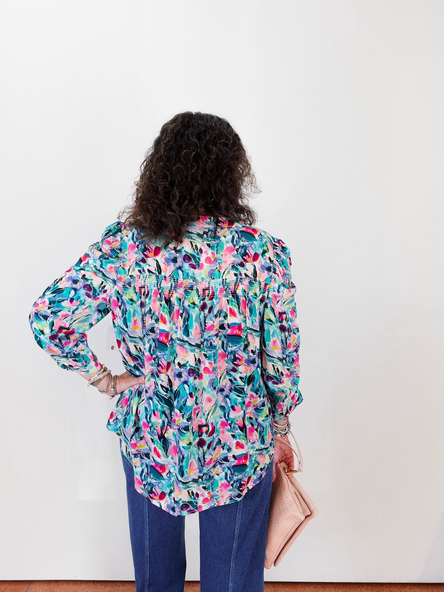 Person wearing a colorful floral blouse against a white background