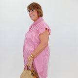 Woman in a pink dress holding a straw bag against a white background