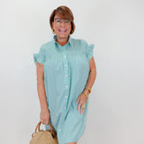 Woman wearing a light blue dress holding a woven handbag against a white background