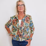 woman wearing a snap front floral print jacket in front a white background 