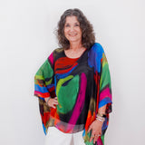 Woman wearing a colorful, patterned top against a white background