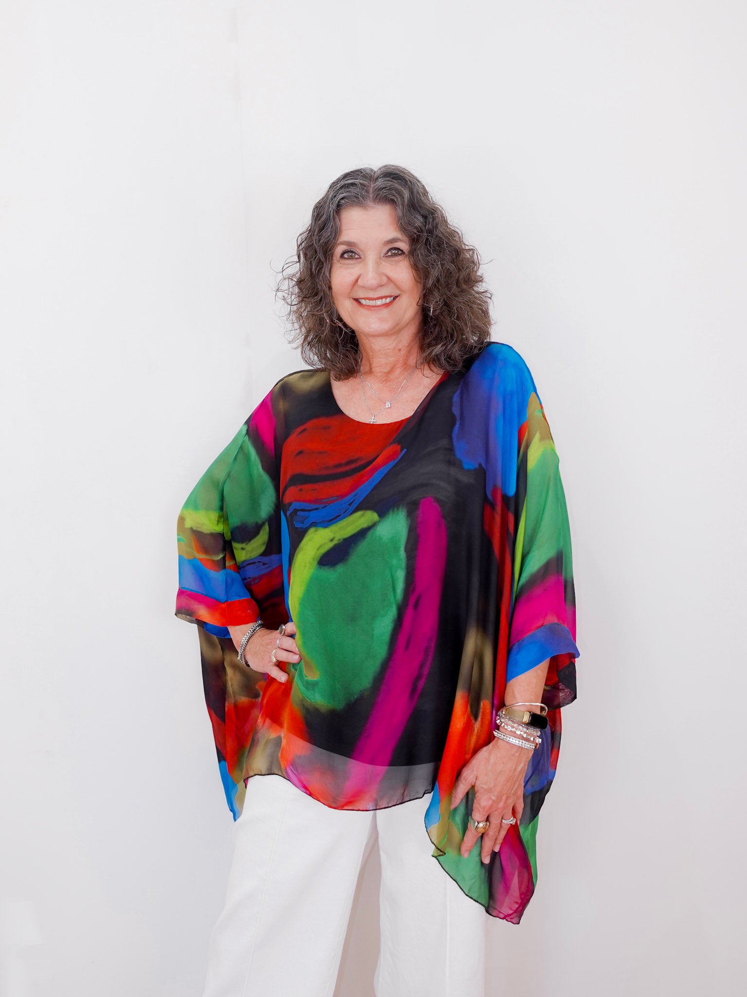 Woman wearing a colorful, patterned top against a white background