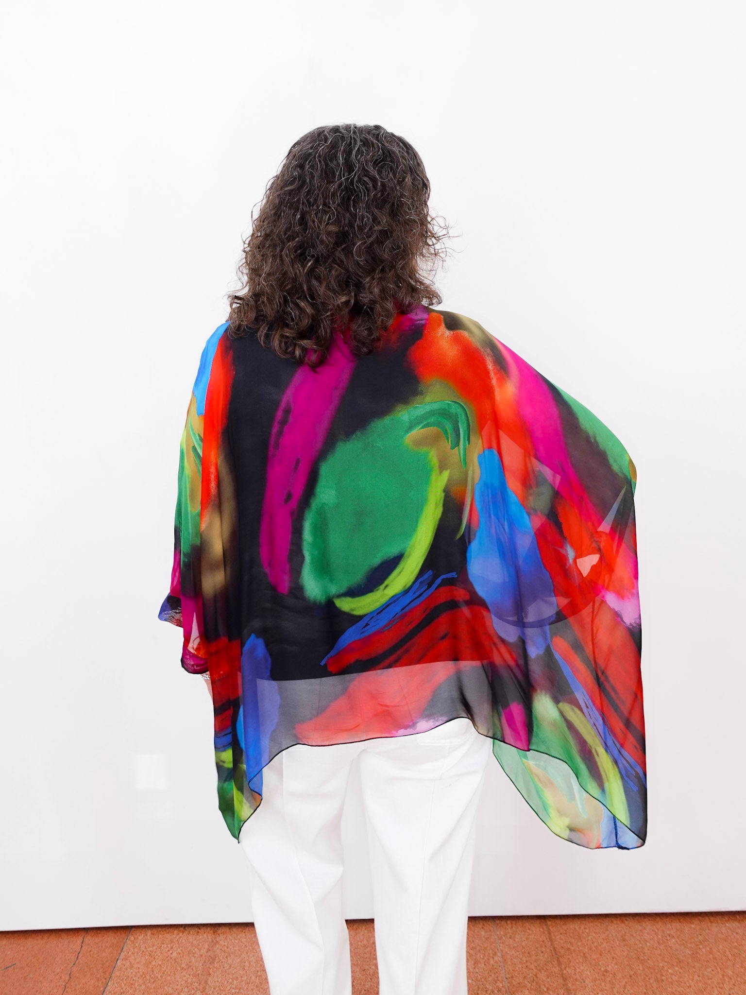 Person wearing a colorful, abstract-patterned shawl on a white background