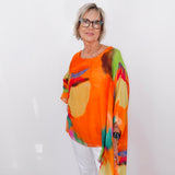 Person wearing a colorful, patterned shirt with an orange background.