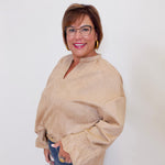 Woman wearing a beige sweater and glasses against a white background