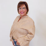 Woman wearing a beige sweater and glasses against a white background