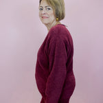 Woman wearing a burgundy outfit against a plain background