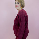 Woman wearing a burgundy outfit against a plain background