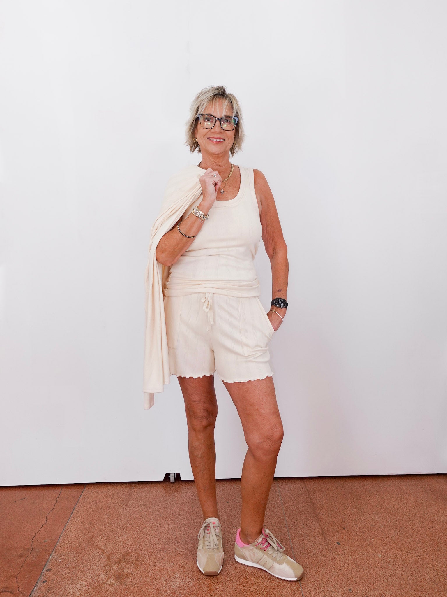 Woman in a white outfit standing against a plain white wall.