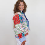 Woman wearing a colorful patchwork jacket with a white background