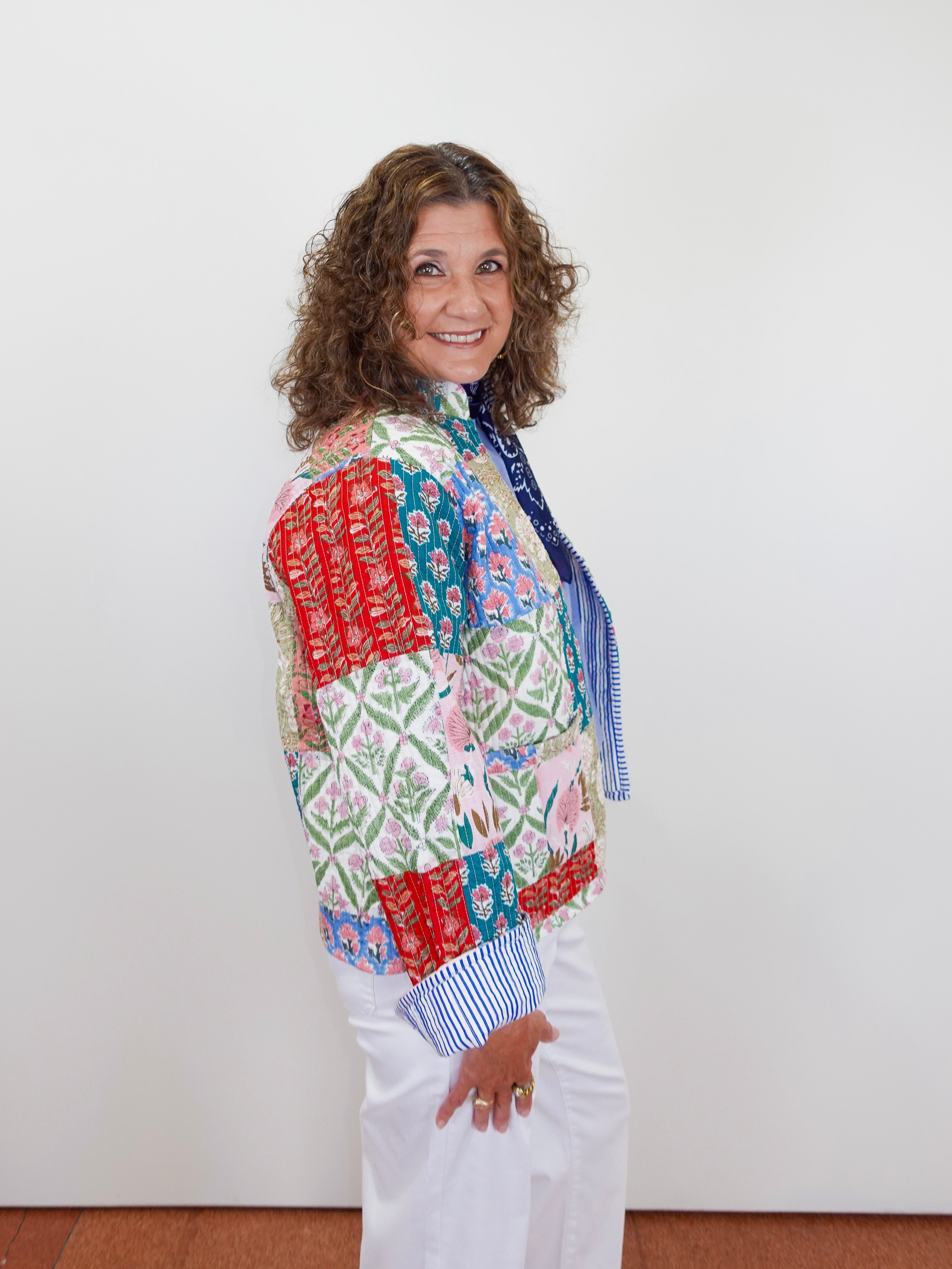 Woman wearing a colorful patchwork jacket with a white background