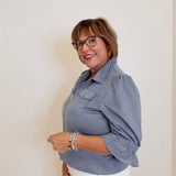 Woman wearing a gray jacket and white pants against a plain background