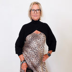 Person wearing a black top and leopard print dress against a white background