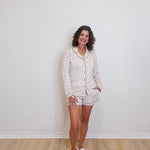 Woman wearing a polka dot pajama set standing against a plain white wall.