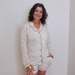 Woman wearing a white pajama set with black patterns against a plain background