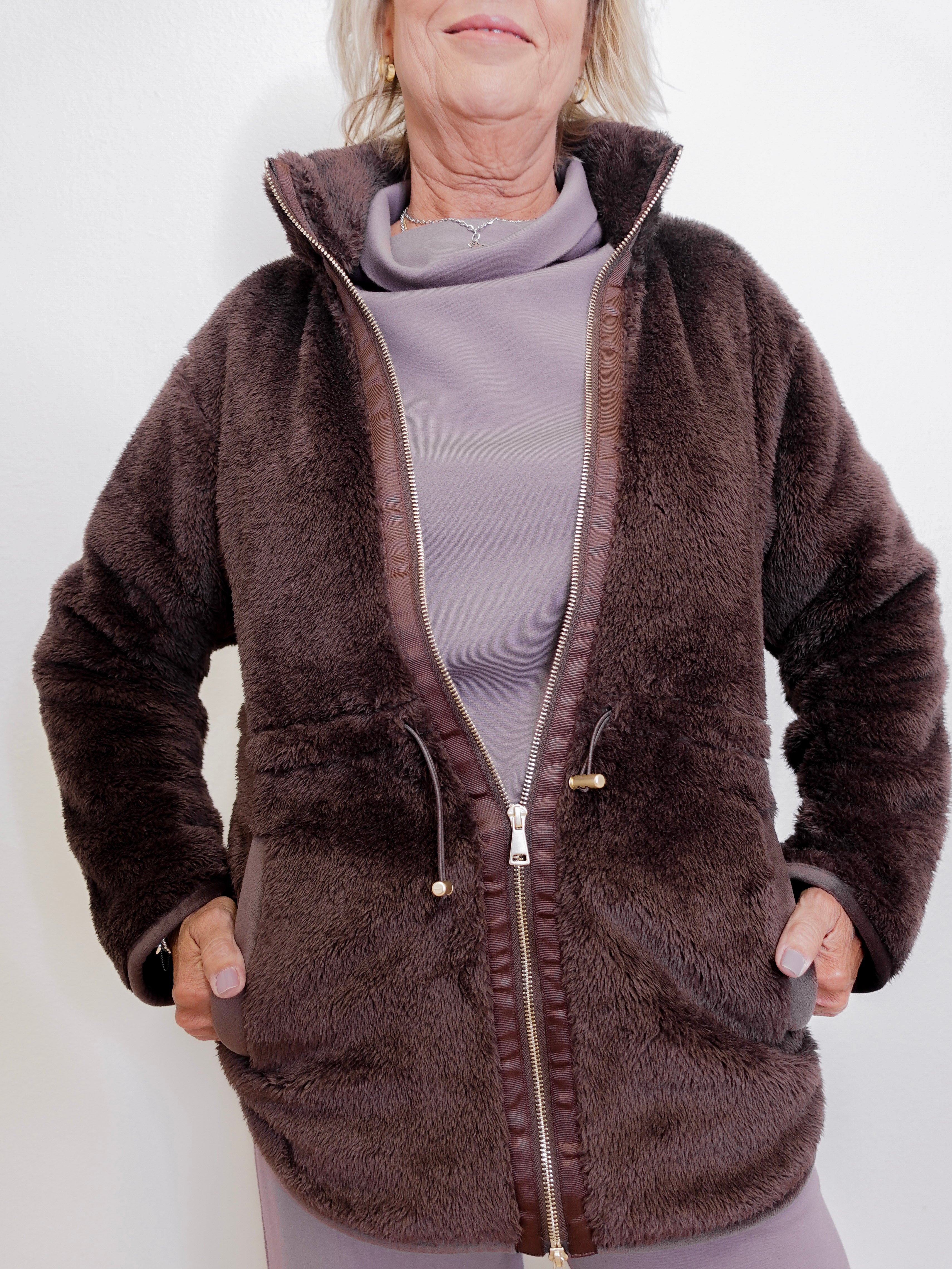 Person wearing a brown fleece jacket on a white background
