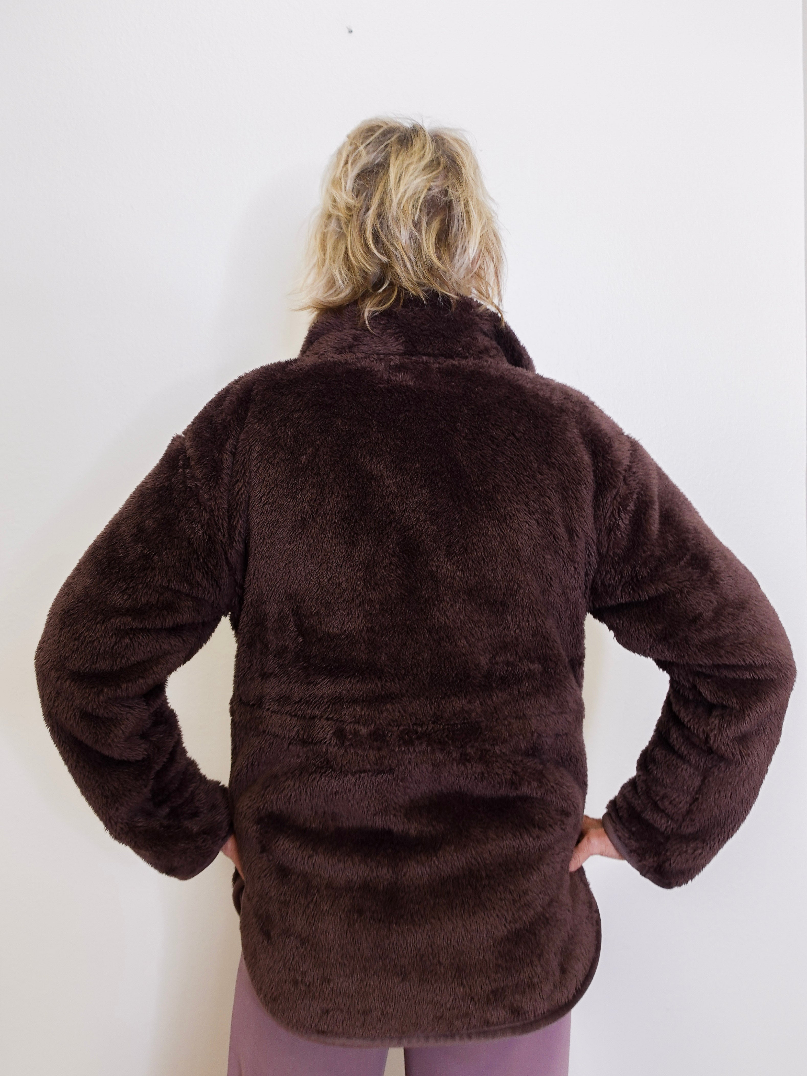Person wearing a brown fleece jacket against a white background