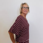 Woman wearing a maroon and white striped outfit against a plain background