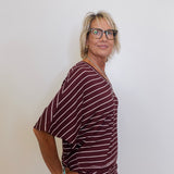 Woman wearing a maroon and white striped outfit against a plain background