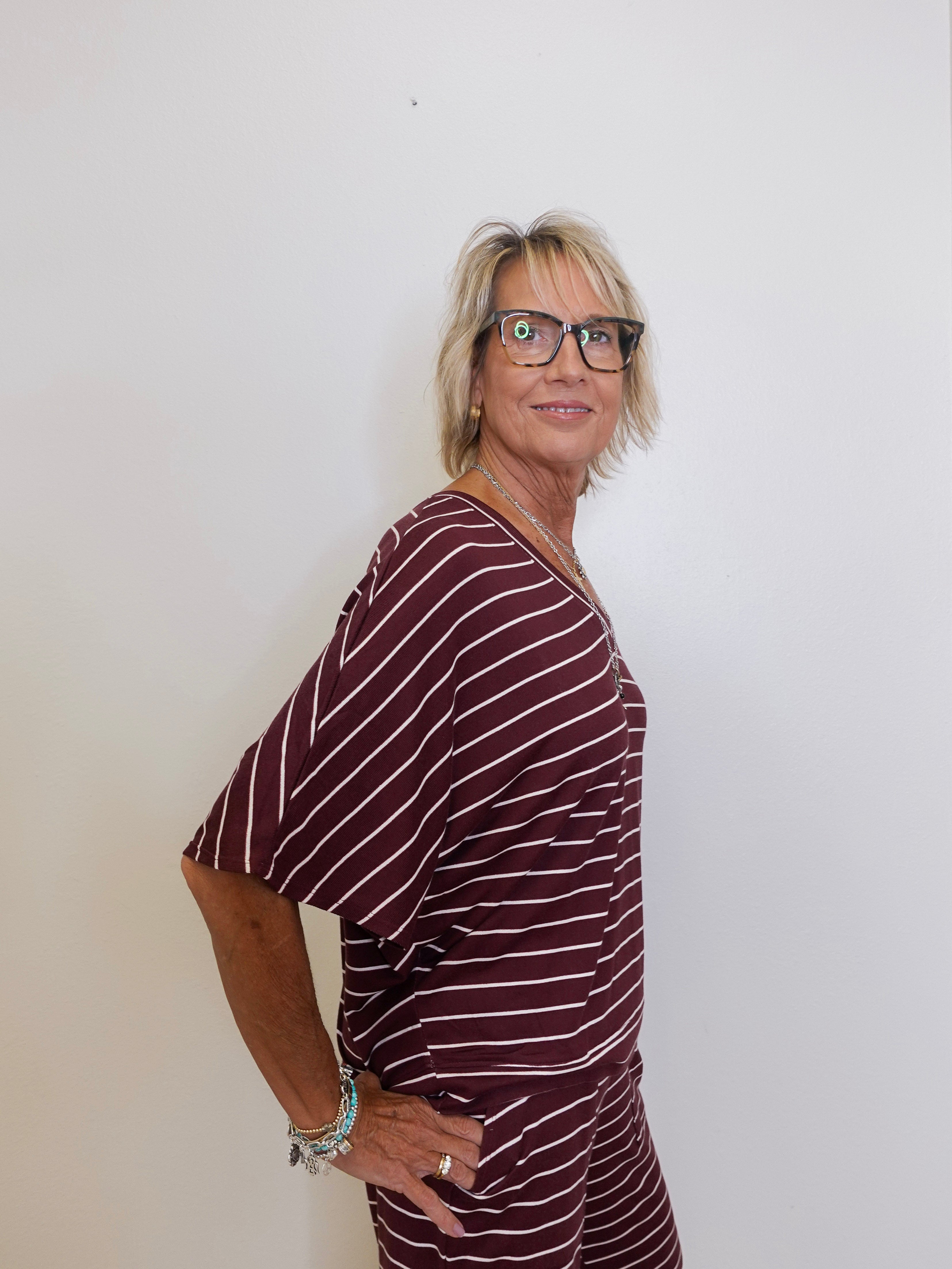 Woman wearing a maroon and white striped outfit against a plain background