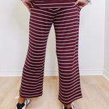 Person wearing a striped outfit with wide-leg pants against a white wall.
