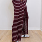 Person wearing maroon and white striped pants with white sneakers on a light wooden floor.