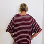 Person wearing a maroon and white striped outfit against a white wall