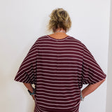 Person wearing a maroon and white striped outfit against a white wall