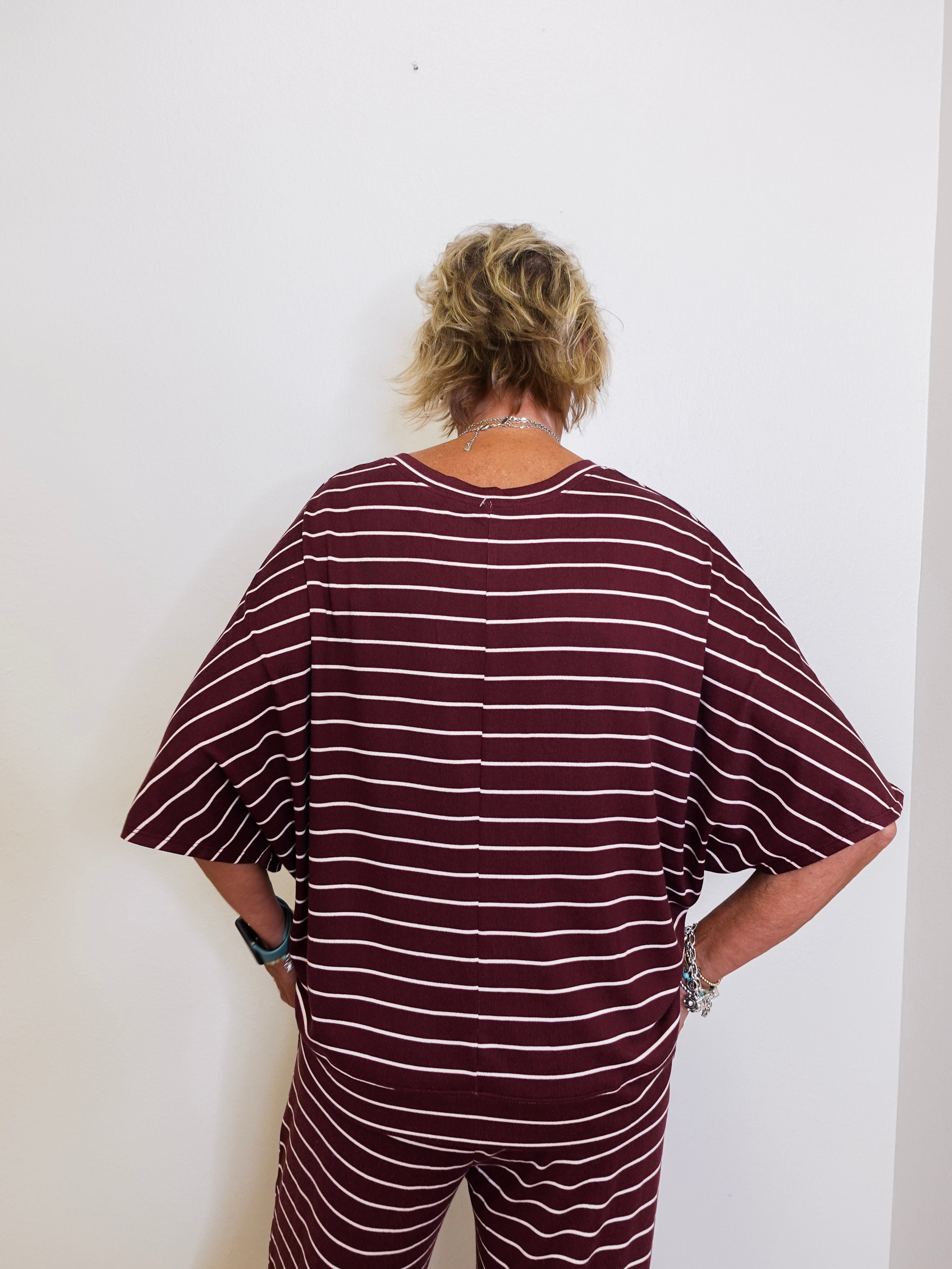 Person wearing a maroon and white striped outfit against a white wall
