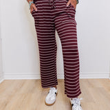 Person wearing a maroon and white striped outfit with white sneakers on a light wooden floor.