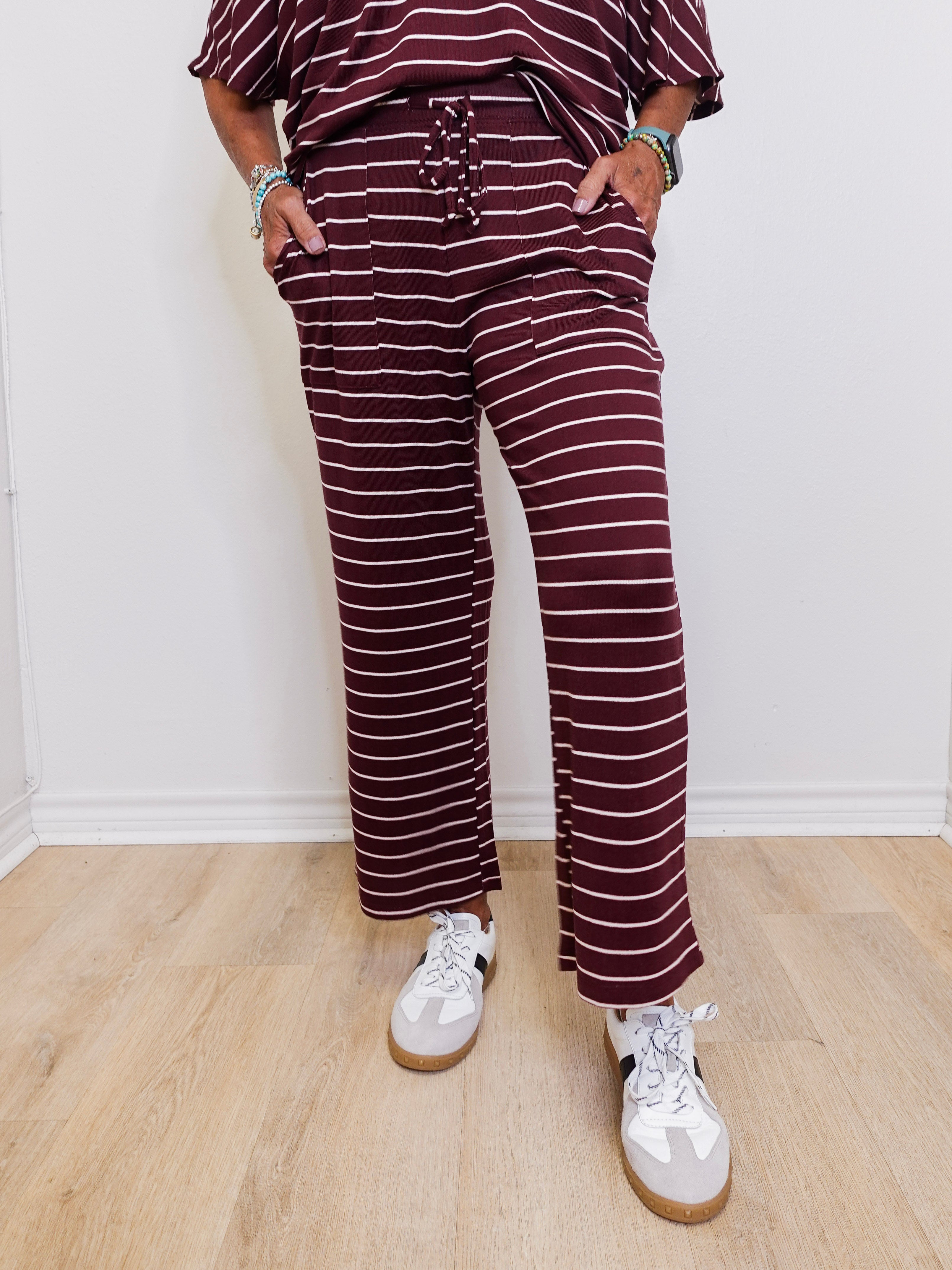 Person wearing a maroon and white striped outfit with white sneakers on a light wooden floor.