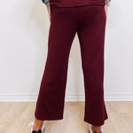 Person wearing a burgundy outfit with wide-leg pants on a light wooden floor.