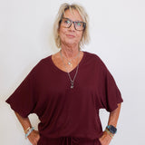 Woman wearing a burgundy outfit with glasses against a white background