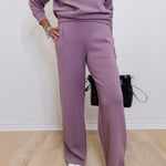 Person wearing a matching purple outfit with a sweater and pants on a plain background